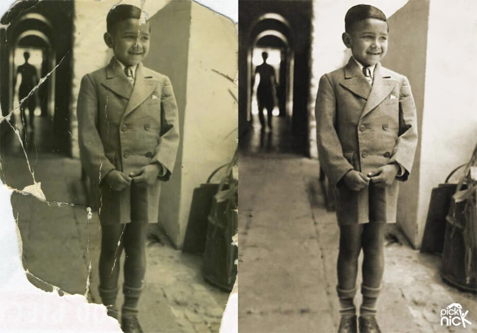 A boy in uniform standing in a corridor. Old photo is damage with torn off sections. Restored with missing sections recreated